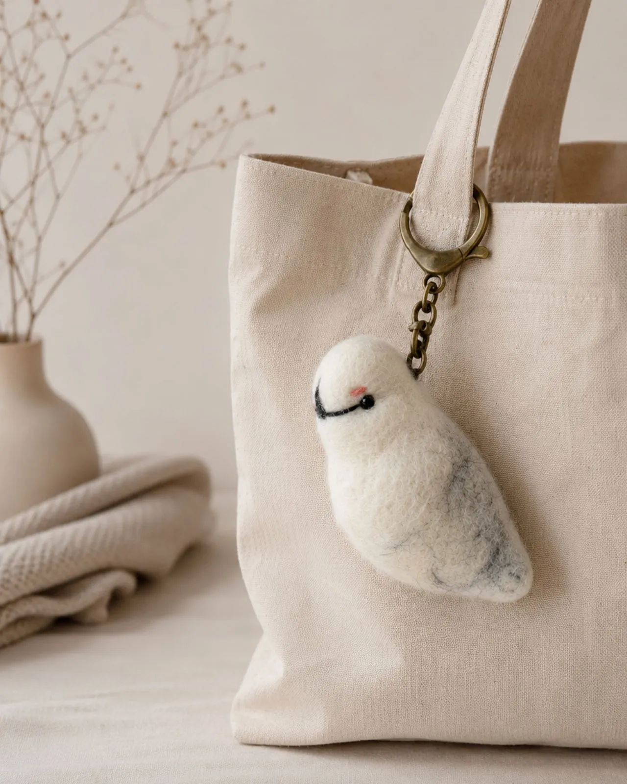Handmade Norwegian AWEBO wool bird bag charm with an individually numbered brass tag, carried on a cotton tote.