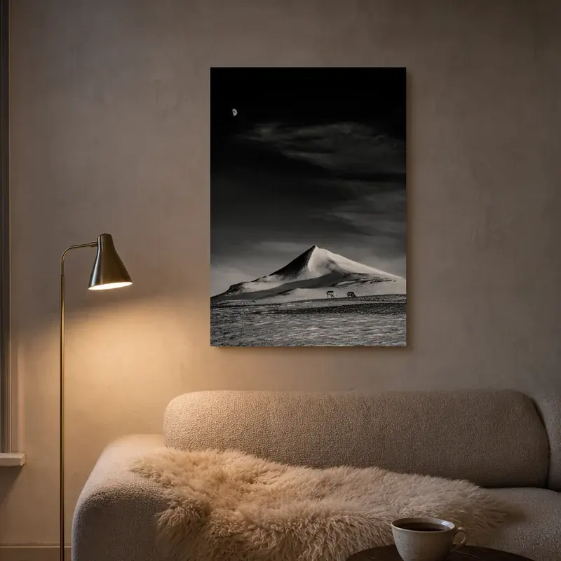 Last Light, an art piece of a lone snow mountain under the moon, above a sofa in a warm living room